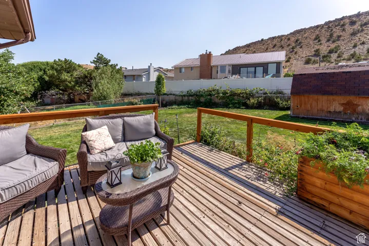 Deck with a fenced backyard, an outdoor living space, and a storage unit