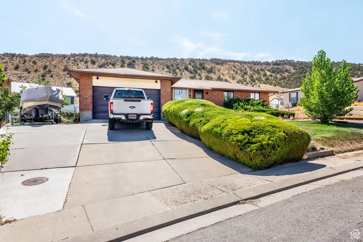 Ranch-style house featuring brick siding, concrete driveway, a garage, and a mountain view