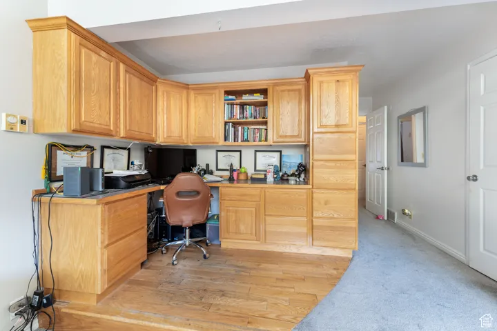 Home office featuring built in desk and light wood finished floors