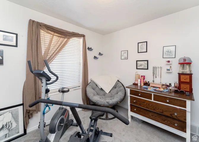 Exercise area featuring light carpet and baseboards