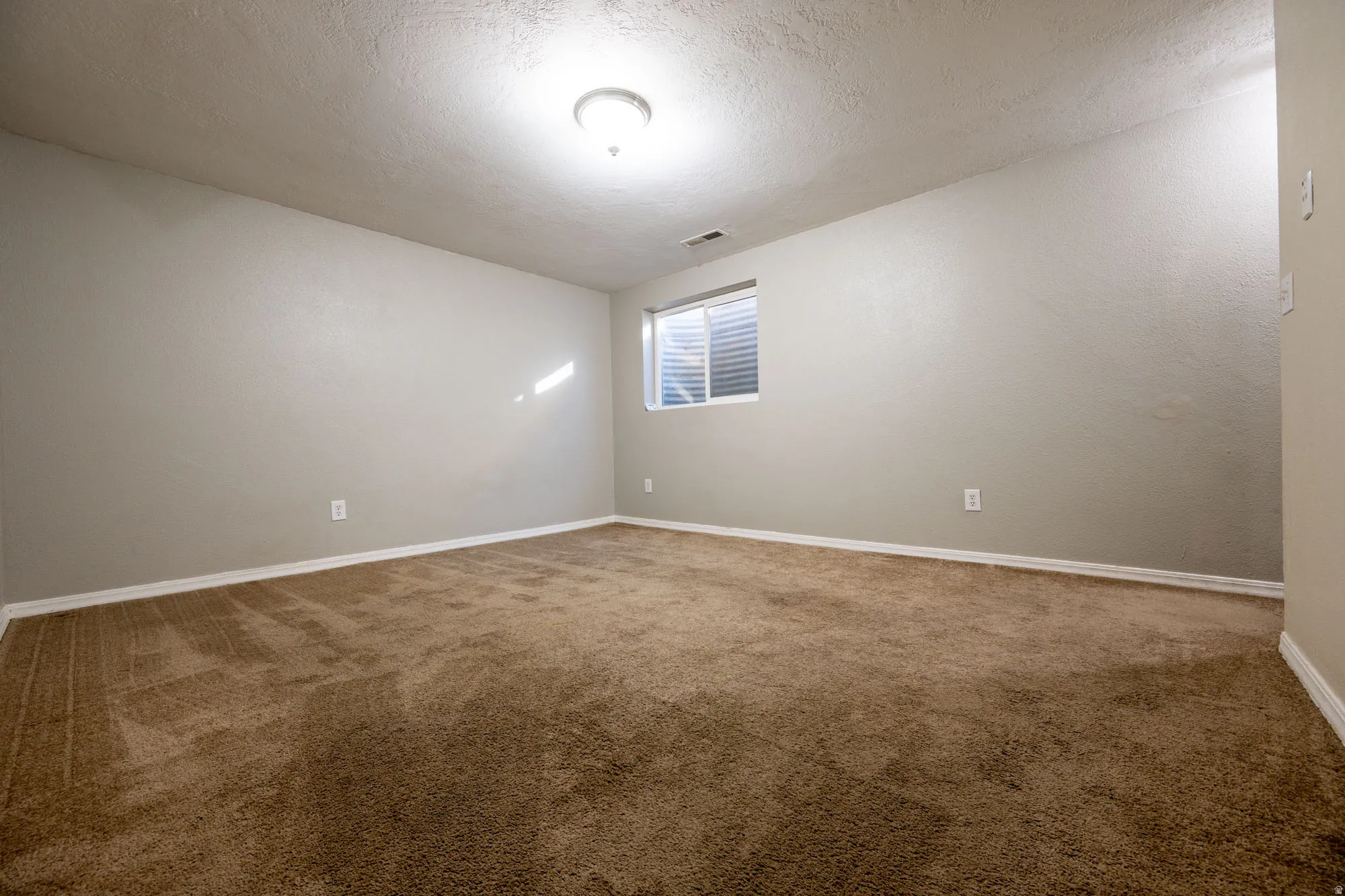 Carpeted family room with a textured ceiling and a textured wall