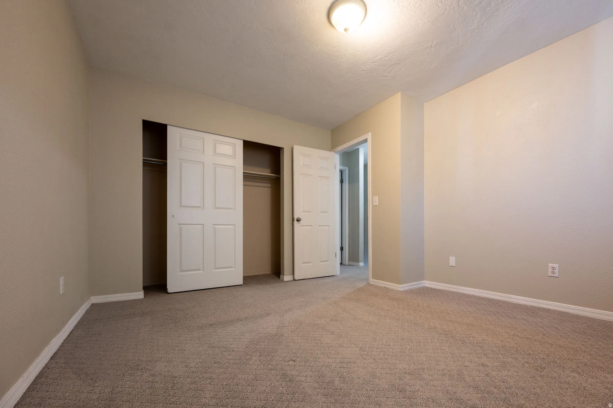 Main bedroom featuring light colored carpet, a closet, and a textured ceiling