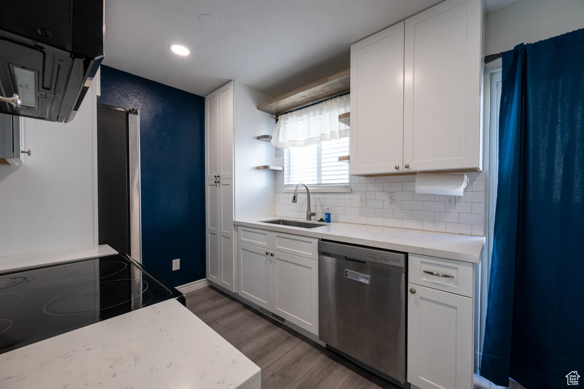 Kitchen with open shelves, stainless steel appliances, dark wood-style flooring, light stone counters, and recessed lighting