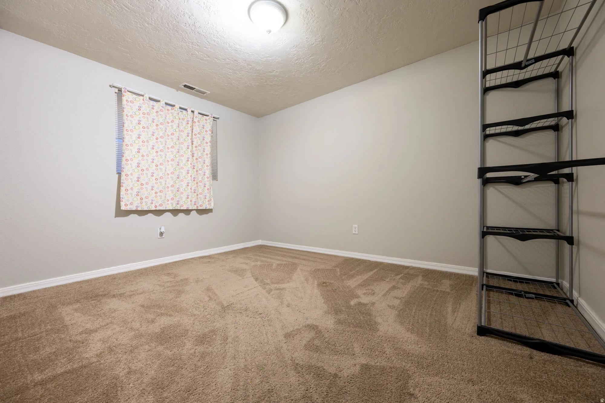 Empty room with light colored carpet and a textured ceiling