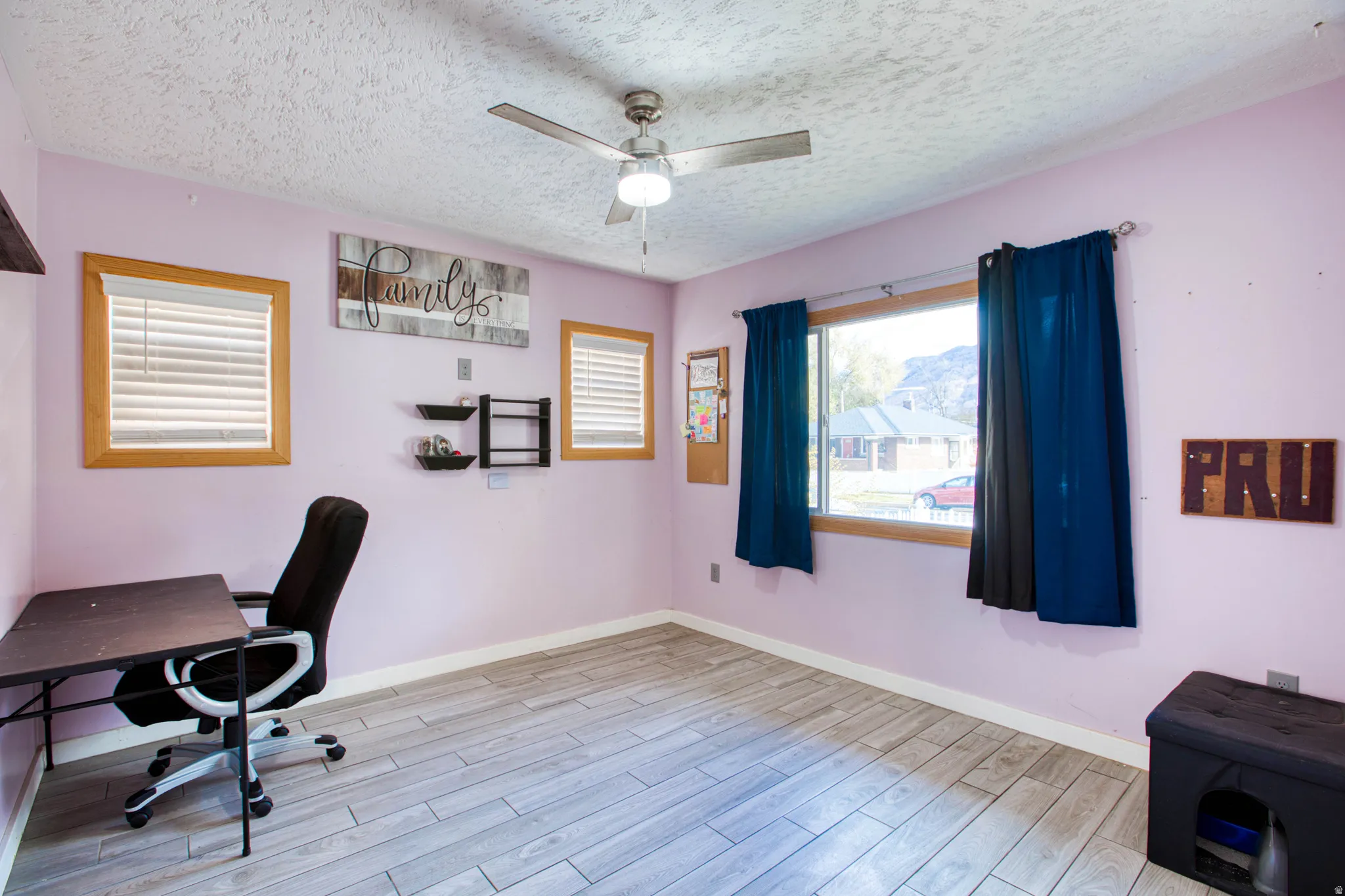 Office with a textured ceiling, light wood-type flooring, and ceiling fan