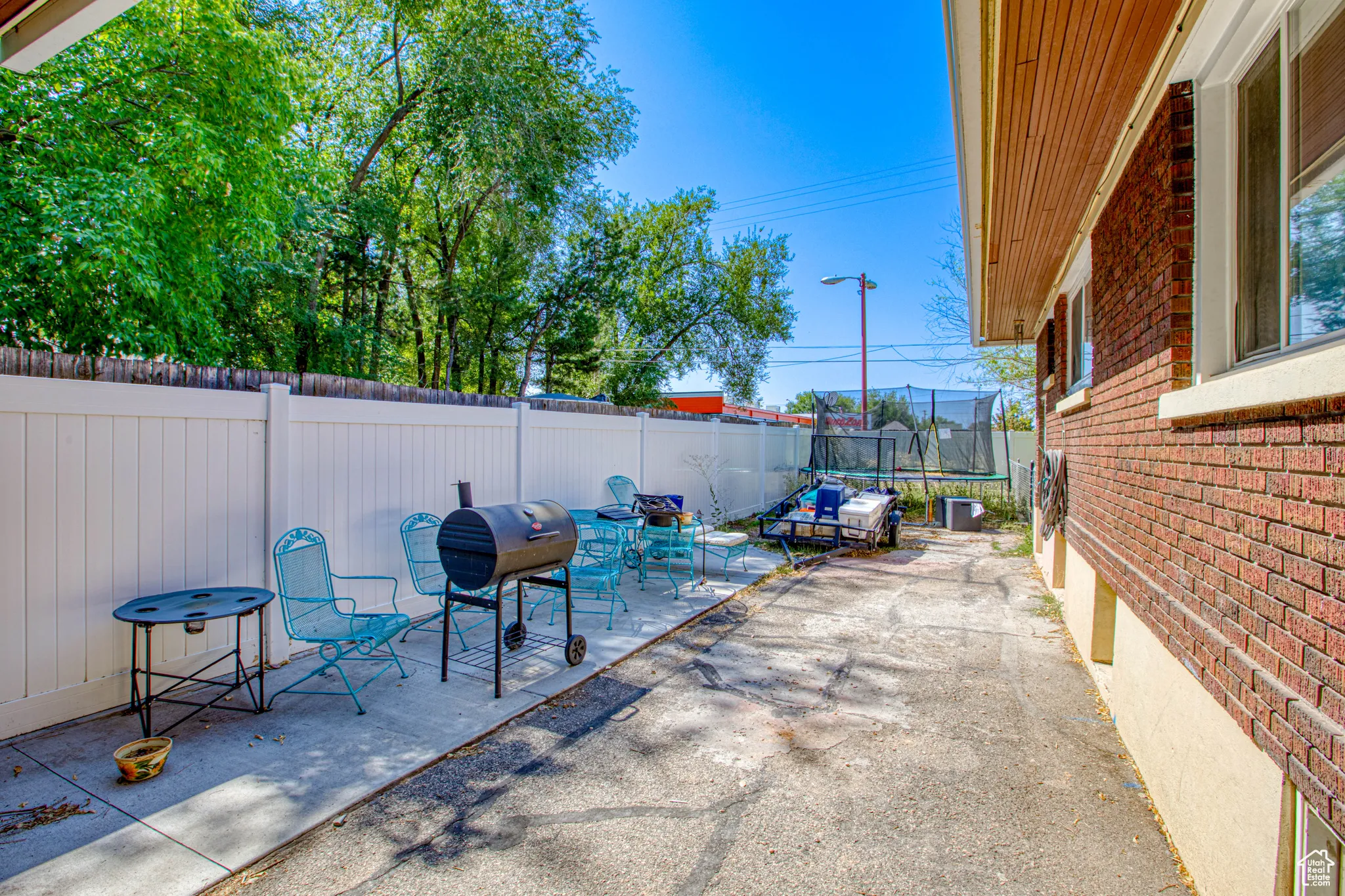 Fenced backyard featuring a trampoline, a patio, and a grill