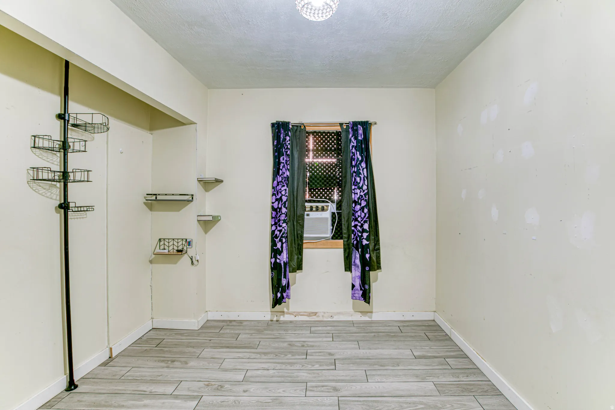 Empty room with wood tiled floors, a textured ceiling, and cooling unit