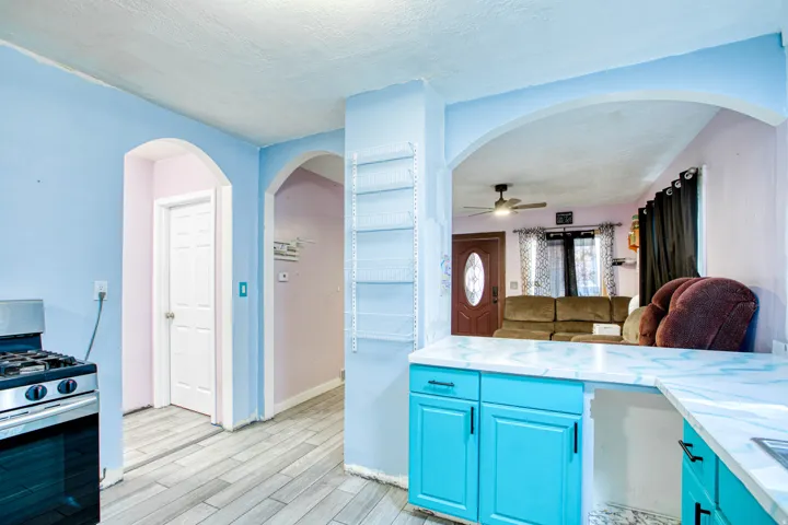 Kitchen featuring arched walkways, stainless steel gas range, wood finish floors, a textured ceiling, and blue cabinets