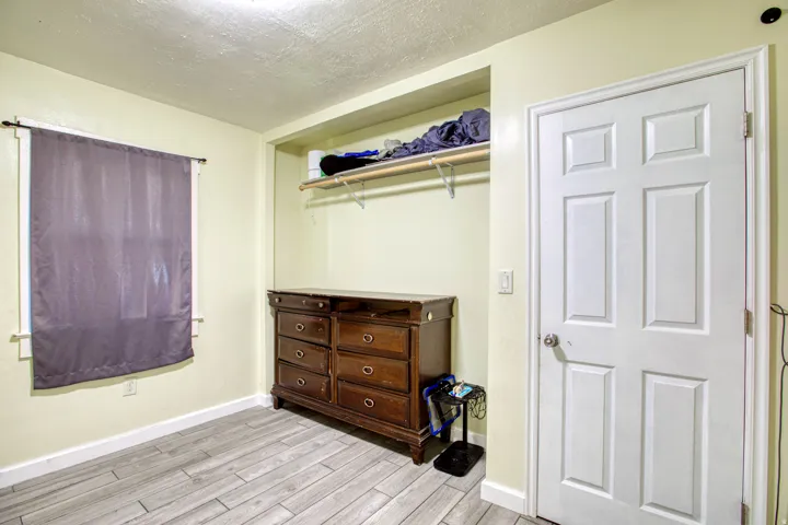Bedroom with a textured ceiling, light wood-style flooring, and a closet