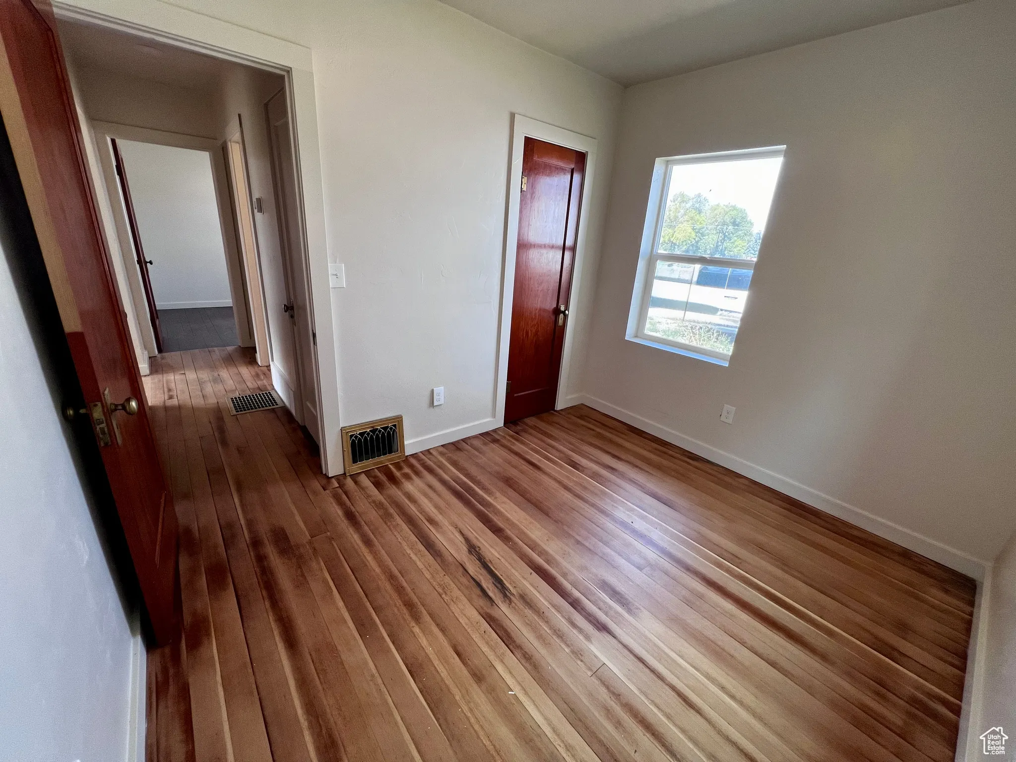 Unfurnished bedroom with baseboards and hardwood / wood-style floors