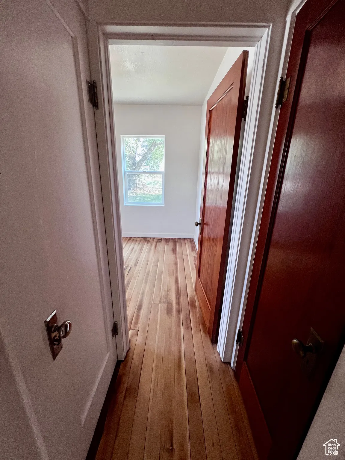 Corridor with dark wood-type flooring and baseboards