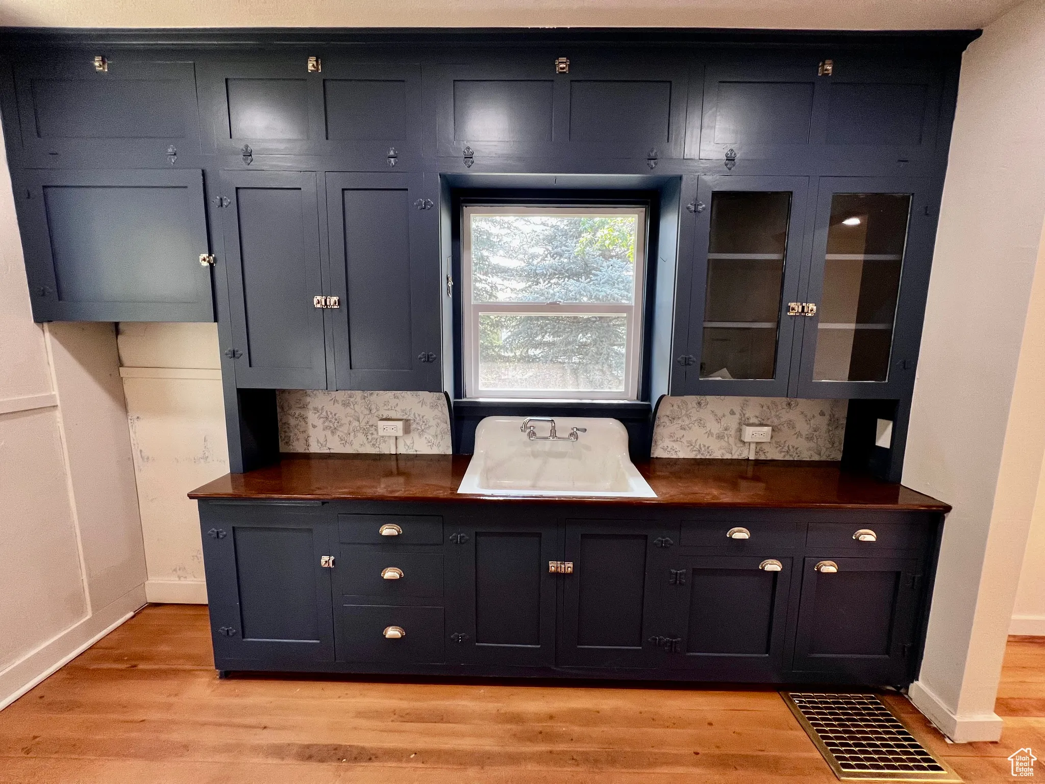 Bar with light wood-style floors and glass insert cabinets