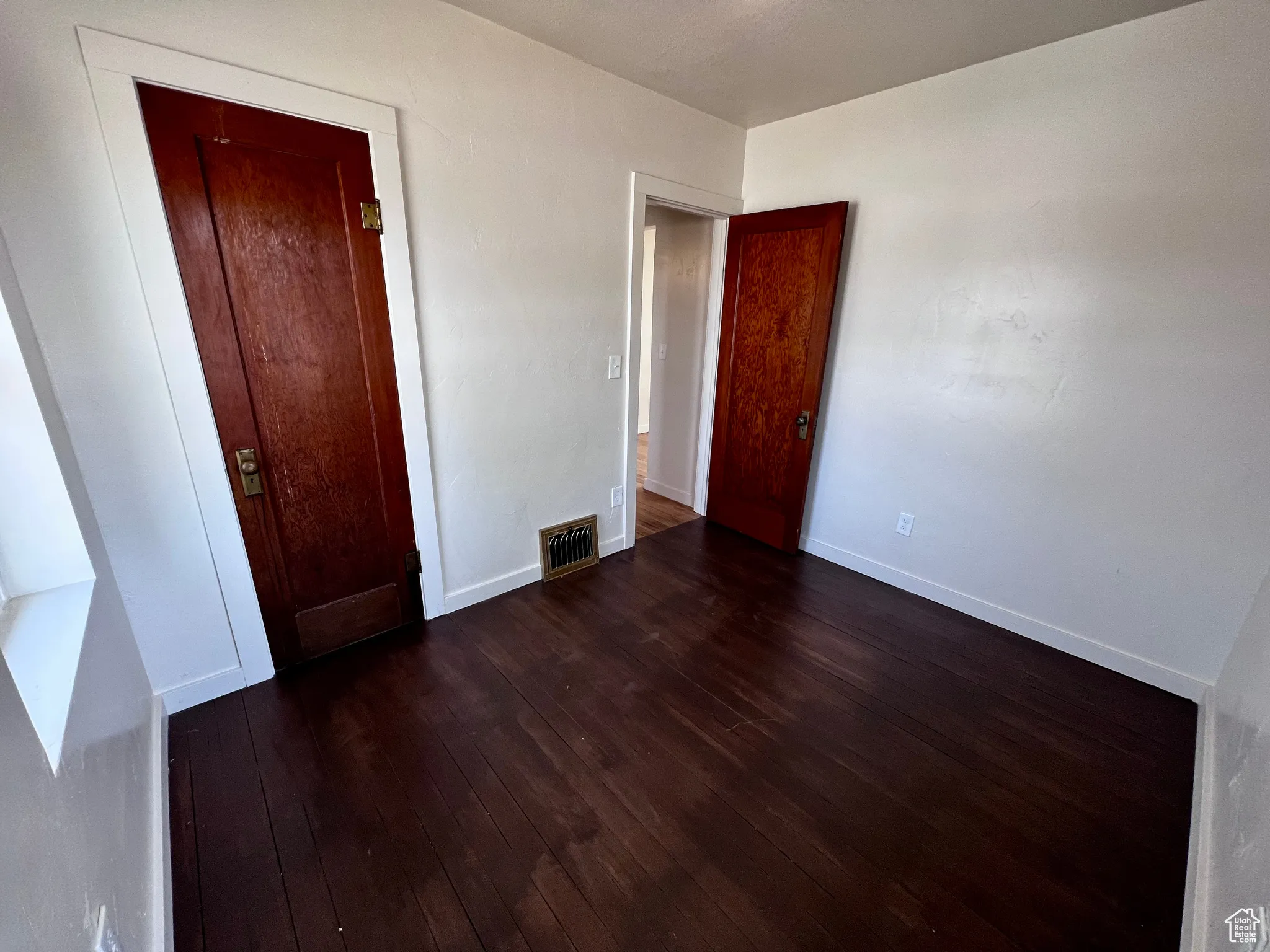 Unfurnished bedroom featuring dark wood finished floors and a closet