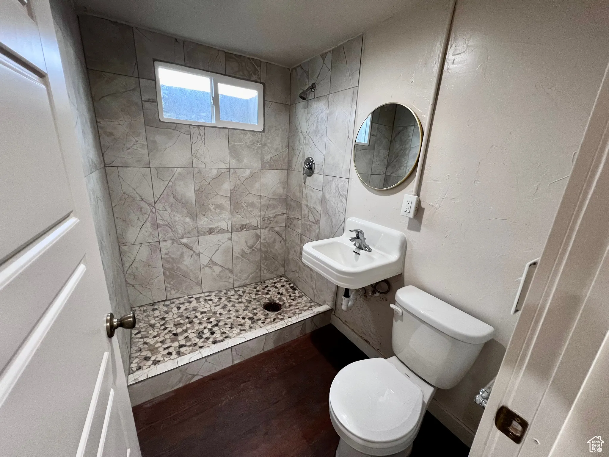 Full bathroom featuring a shower stall, a textured wall, and dark wood-type flooring