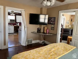 Bedroom with dark wood-style floors, a textured ceiling, a ceiling fan, and ensuite bath