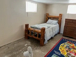 Bedroom featuring baseboards and unfinished concrete floors
