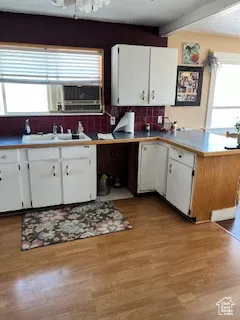 Kitchen featuring white cabinetry, a textured ceiling, backsplash, light wood-style flooring, and light countertops