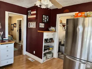 Kitchen featuring freestanding refrigerator, a textured ceiling, light wood finished floors, and ceiling fan