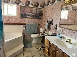 Bathroom featuring vanity, a bath, light tile patterned floors, and wallpapered walls