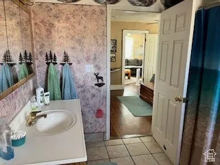 Full bathroom featuring light tile patterned floors, vanity, and wallpapered walls