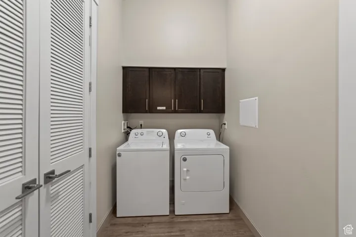 Laundry room with cabinet space, independent washer and dryer, and wood finished floors
