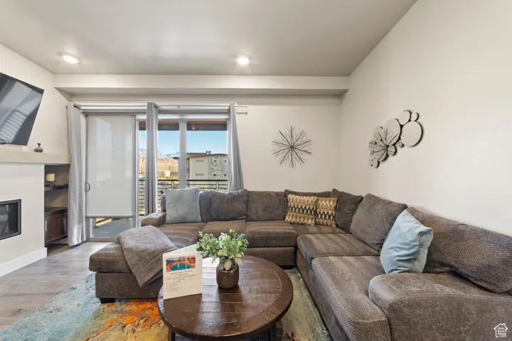 Living area featuring wood finished floors and a glass covered fireplace