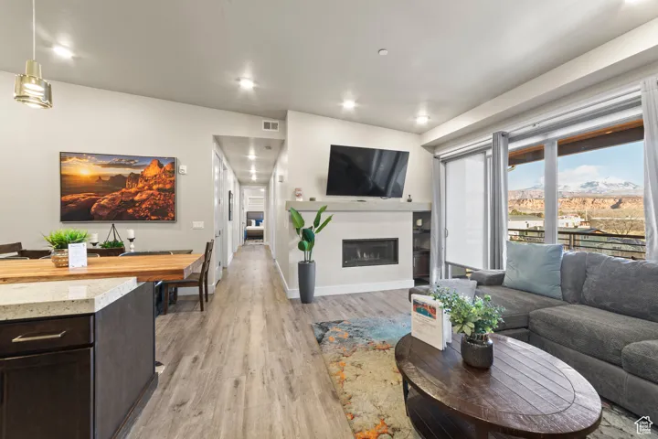 Living room with a glass covered fireplace, light wood-type flooring, and recessed lighting