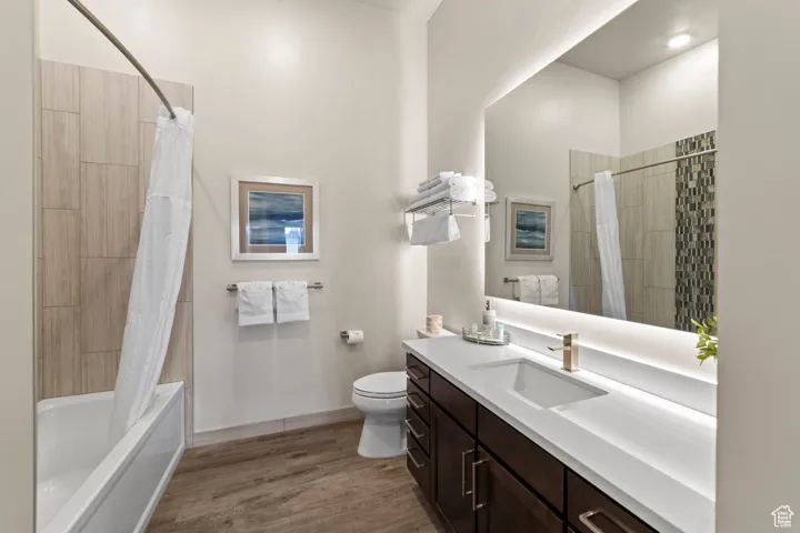 Bathroom with shower / bath combo with shower curtain, light wood-style floors, and vanity