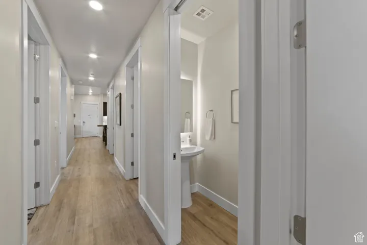 Hallway with light wood-type flooring and recessed lighting