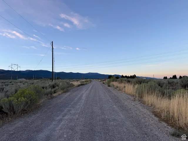 View of dirt / gravel road featuring a mountain view and a view of countryside
