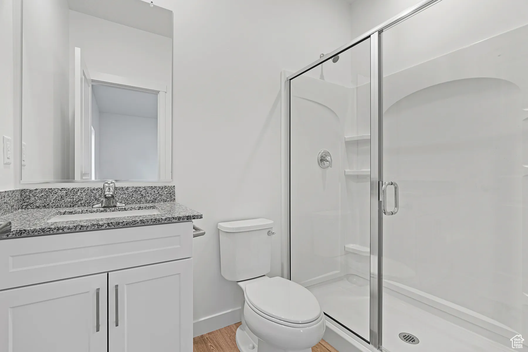 Full bath with vanity, a shower stall, and light wood-style flooring