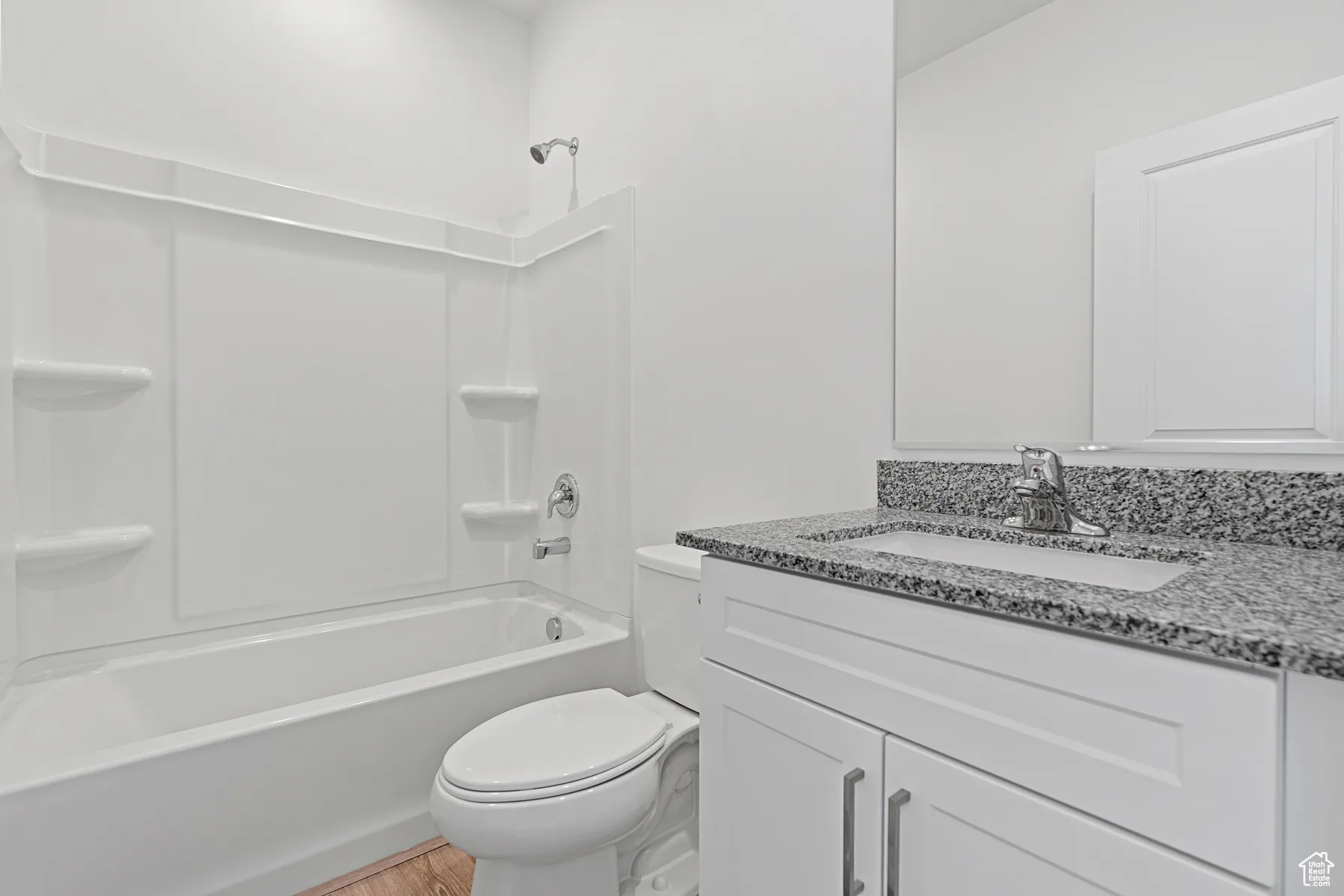 Bathroom with washtub / shower combination, vanity, and light wood-style flooring