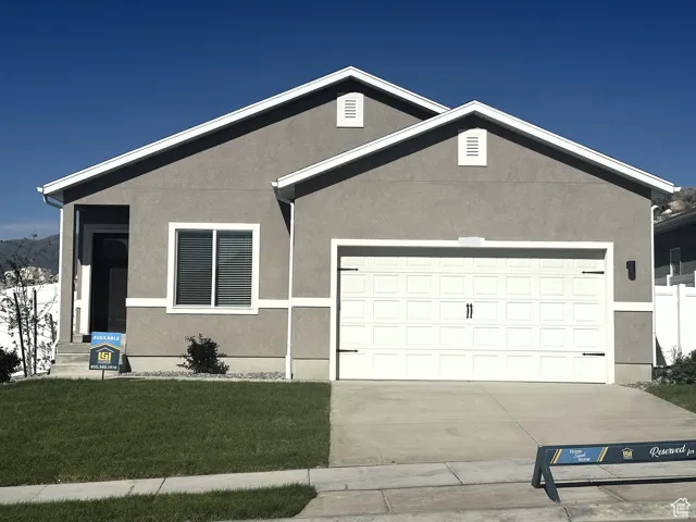 View of front of house featuring driveway, a garage, stucco siding, and a front yard