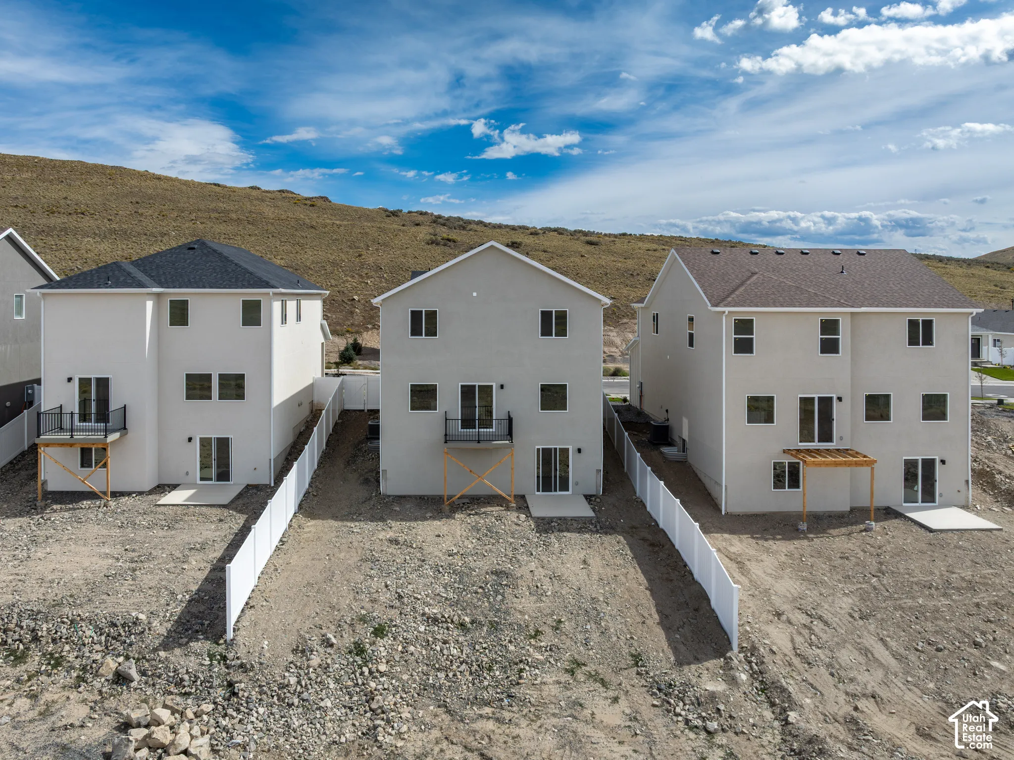 Rear exterior with multiple balconies, ground-level patios, and a privacy fence