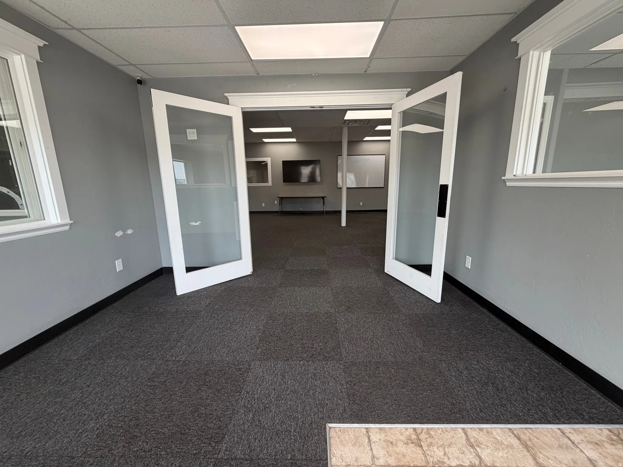 Spacious interior featuring a neutral color palette, recessed lighting, carpet tile flooring, and white trim molding around windows and doors