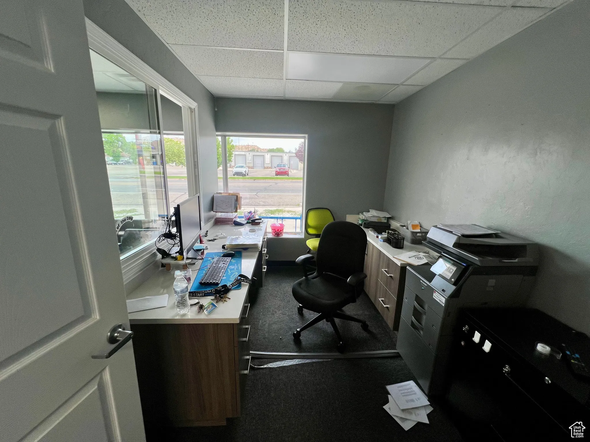 Office area with a paneled ceiling and dark carpet