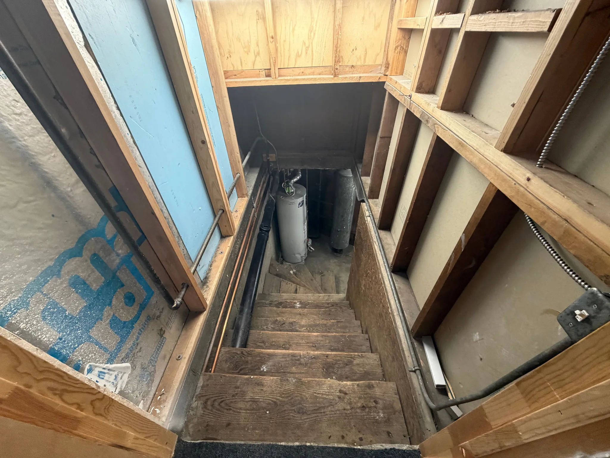 Utility space featuring exposed wood framing and a wooden staircase