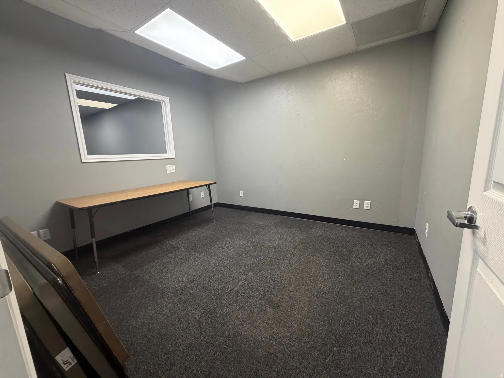 Interior space featuring grey walls, dark grey carpet flooring, and a white interior door with a lever handle