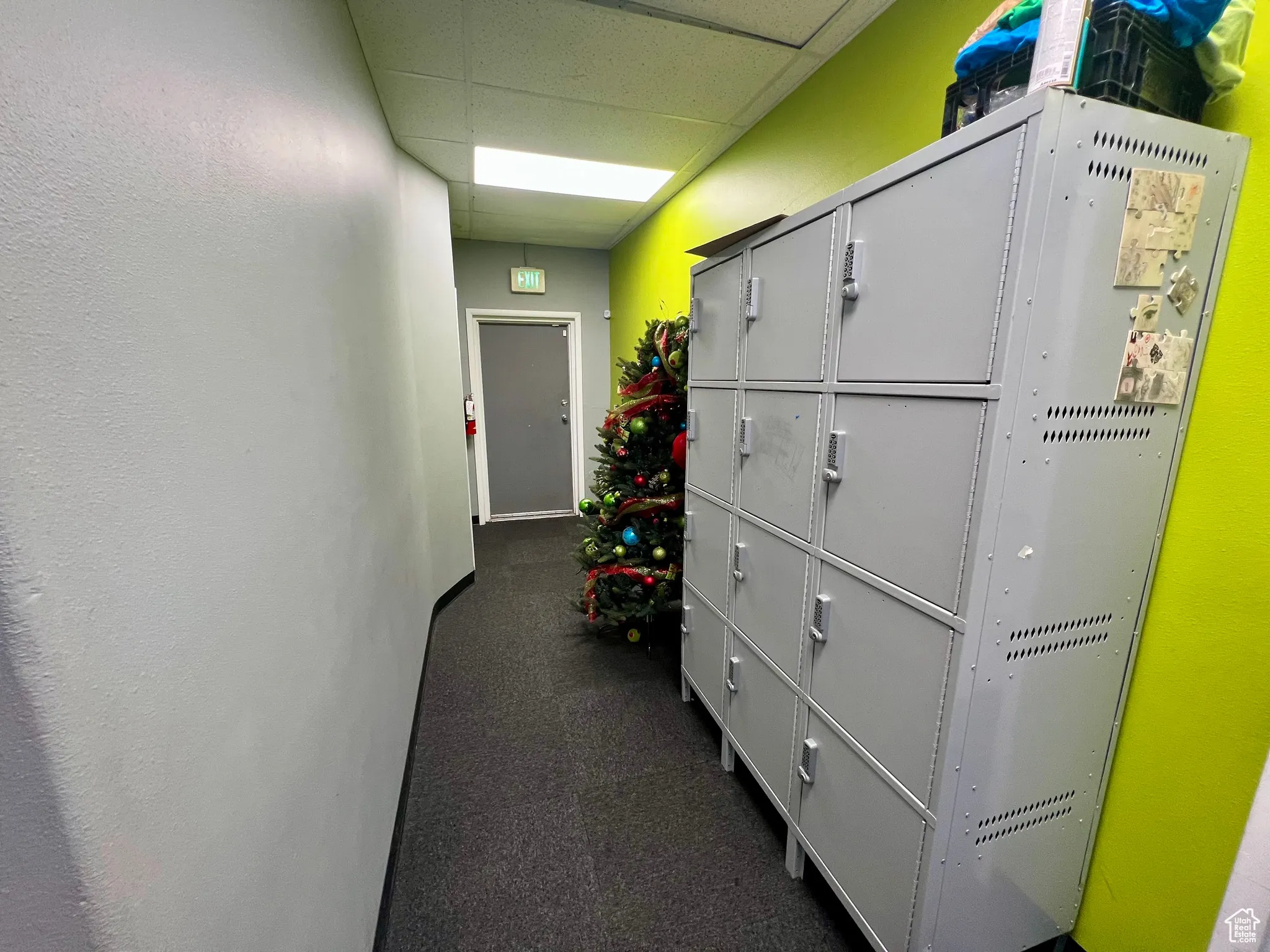 Hall with a paneled ceiling and dark colored carpet