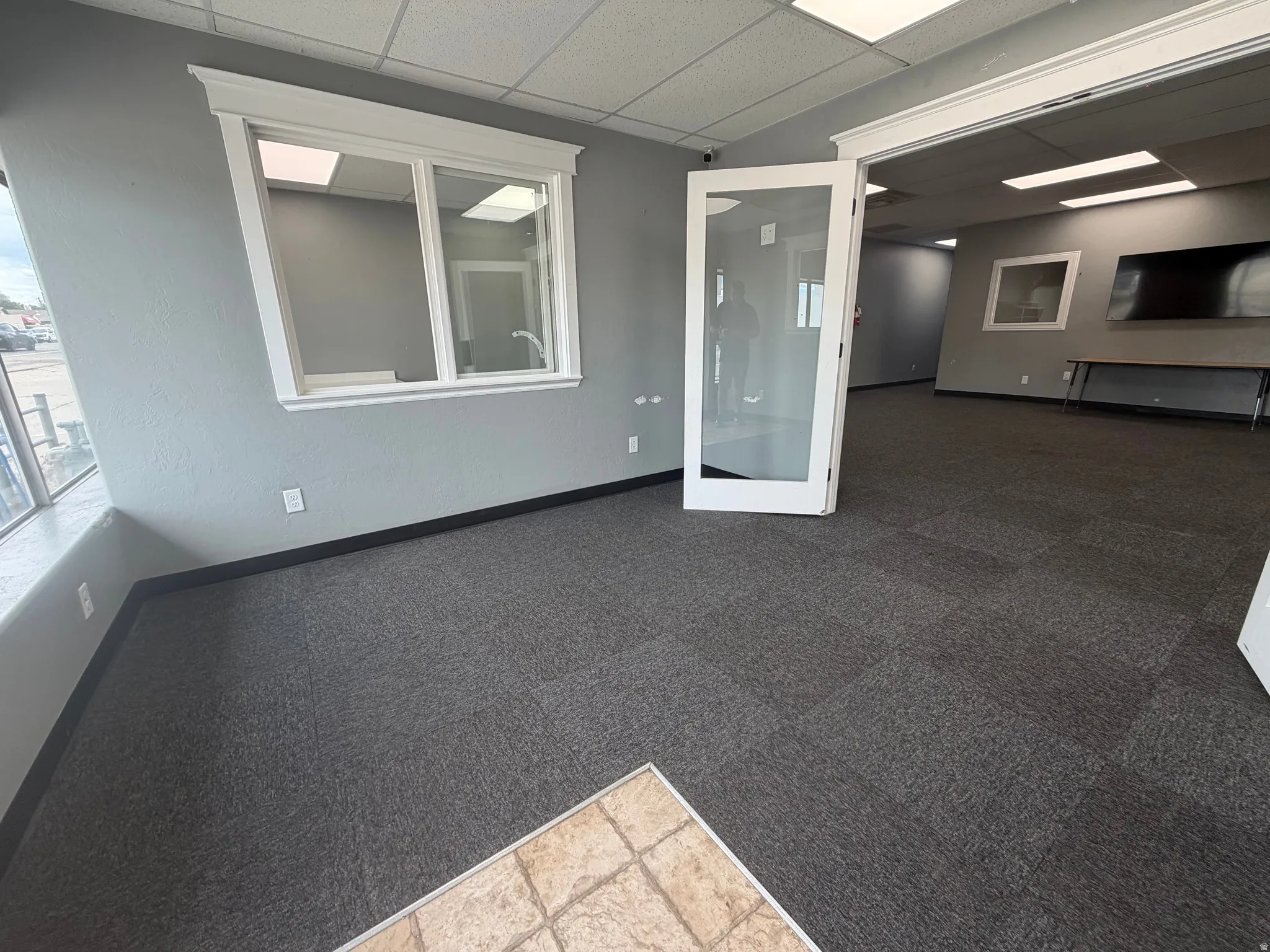 Spacious interior featuring a frosted glass French door entry, gray textured carpet, and neutral gray walls
