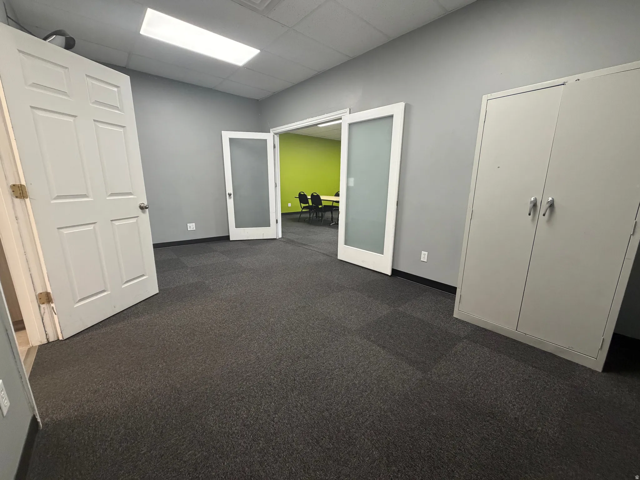 Spacious room featuring neutral gray walls and dark carpet tile flooring