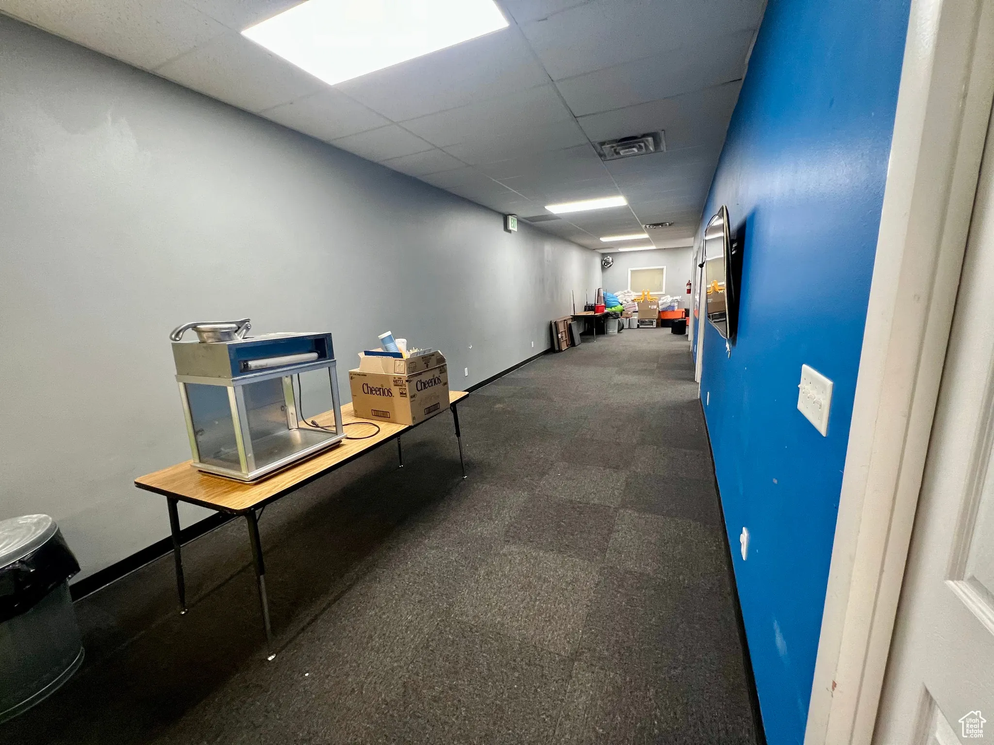 Hallway with a drop ceiling and baseboards