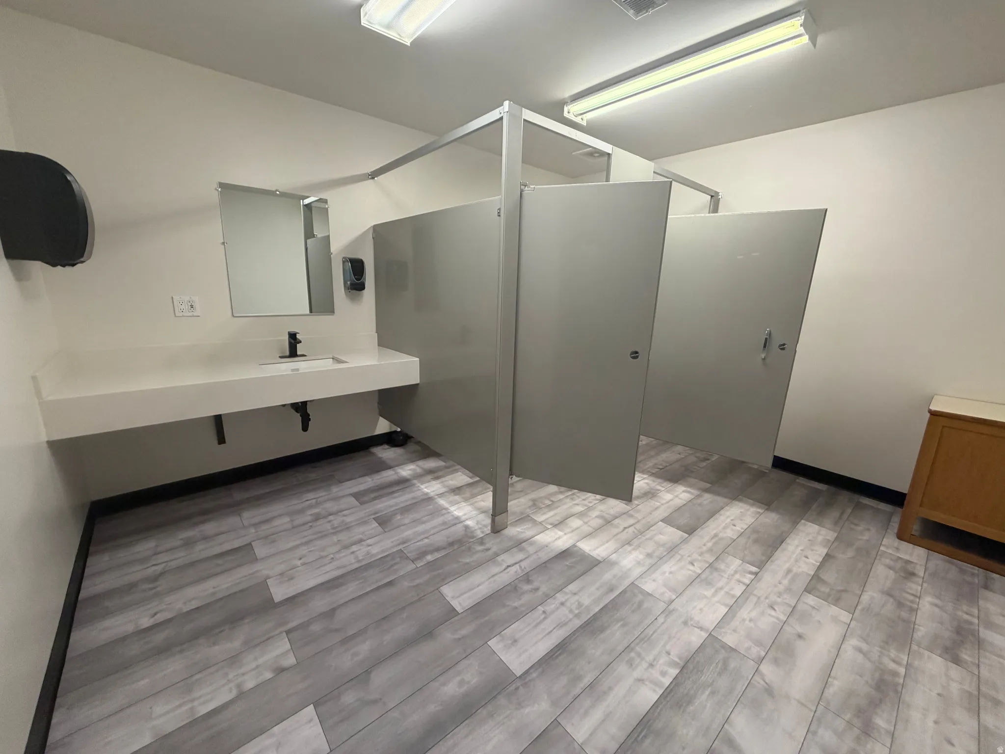 Restroom featuring light wood-finish flooring, white walls, and bright overhead lighting