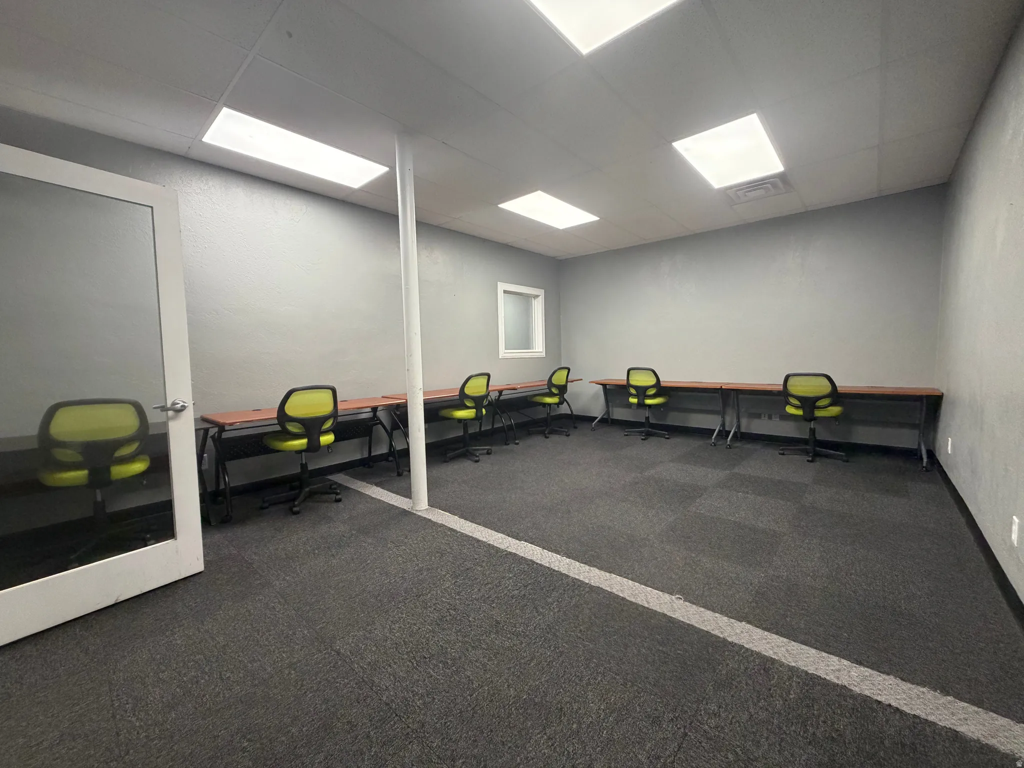 Spacious room featuring modular carpet tile flooring, a window, and recessed rectangular lighting