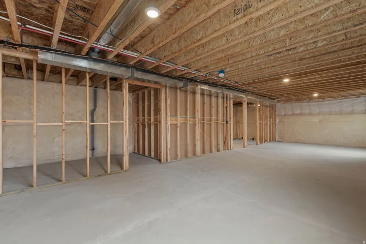 Unfinished basement featuring extensive wood framing, concrete flooring, exposed ceiling joists, and recessed lighting