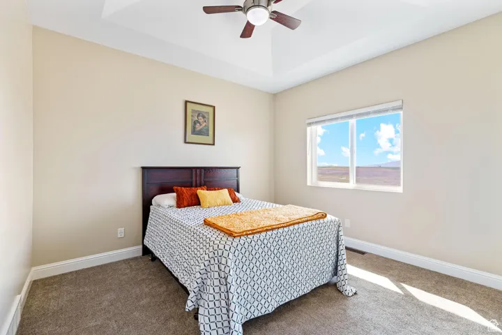 Second bedroom with a ceiling fan and a raised ceiling