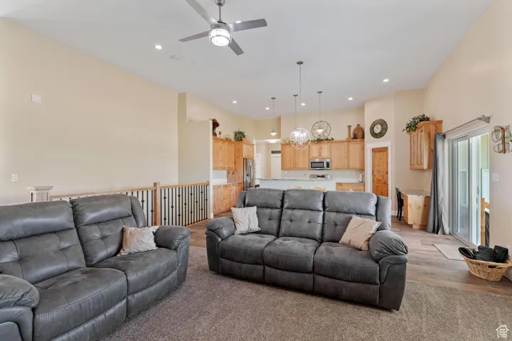 Living room featuring recessed lighting, a ceiling fan, light wood finished floors, and a towering ceiling