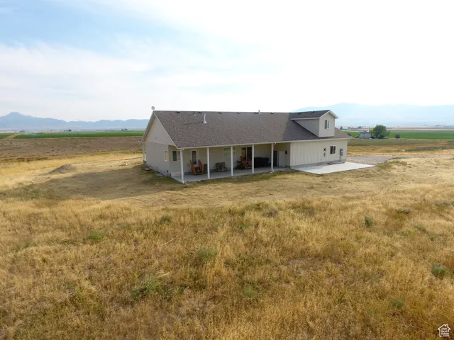 View of front of house with a mountain view, a view of countryside, a patio area, and a shingled roof