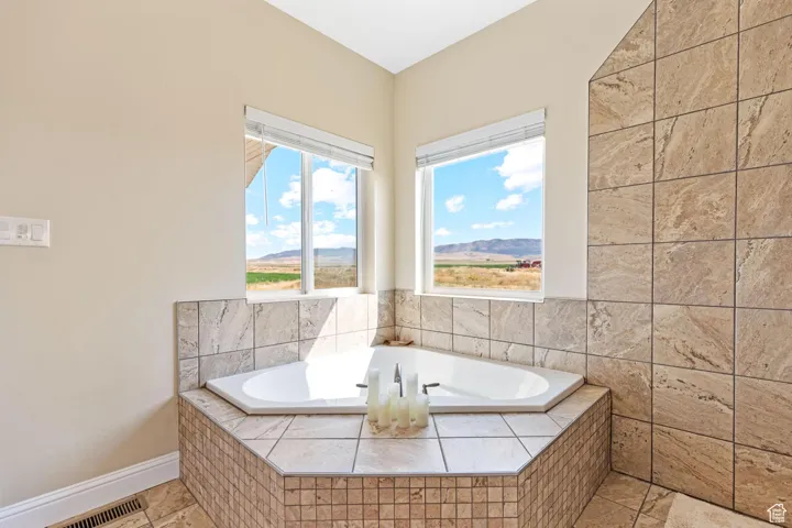 Main bathroom with a bath, a mountain view, and light tile patterned flooring