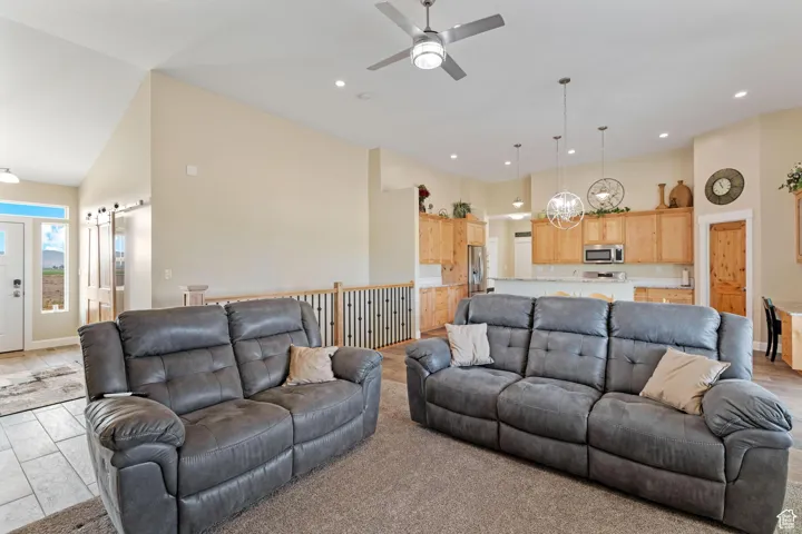 Living area featuring high vaulted ceiling, a ceiling fan, recessed lighting, a barn door, and a chandelier